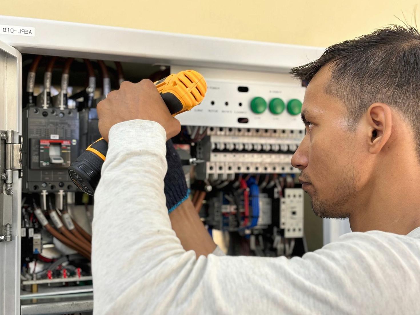 Professional electrician working on switchboard